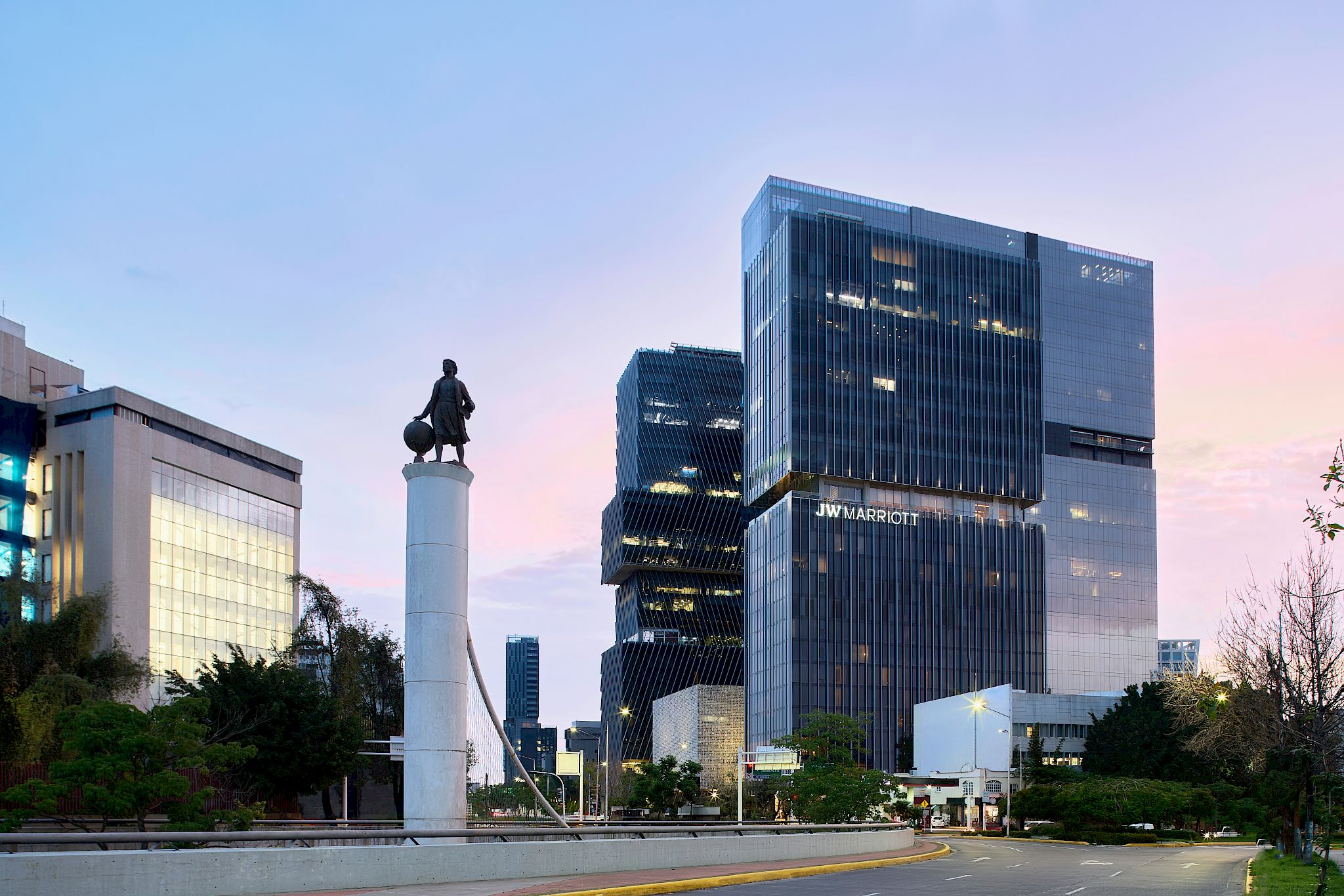 a statue of a man on a pillar in front of a city