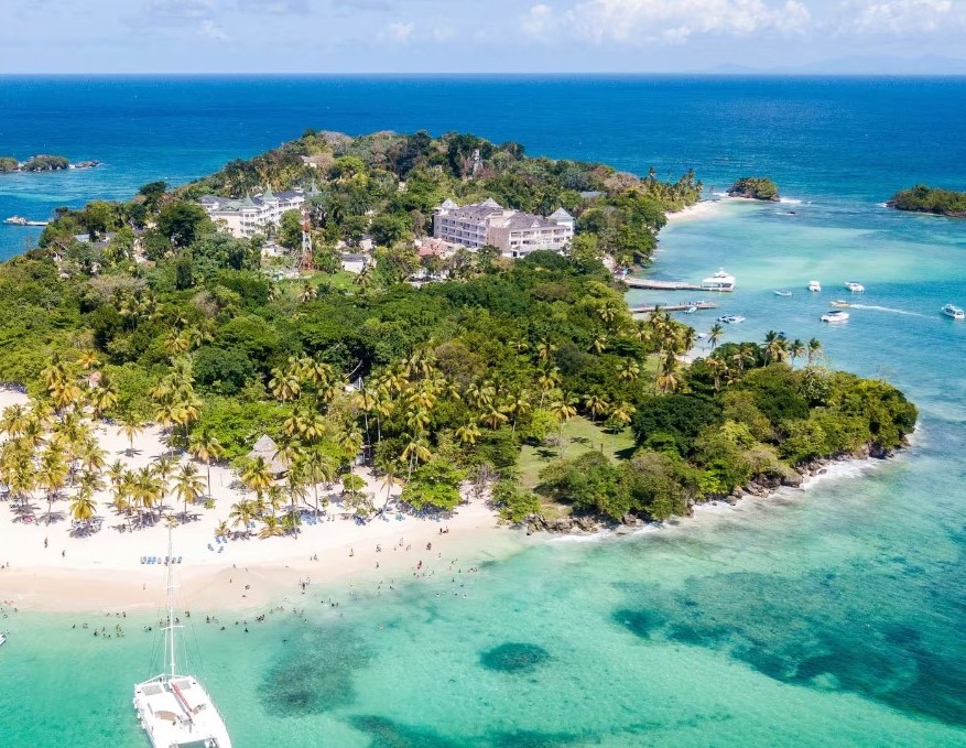 a white boat on a beach with trees and a body of water